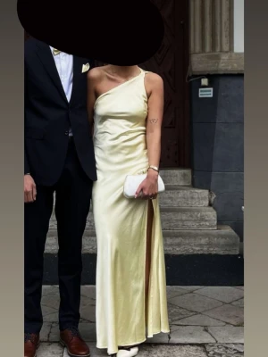 Gul balklänning från Showpo - Säljer en superfin gul balklänning från Showpo i satinliknande material. Klänningen har oneshoulder-design, öppen rygg med snygg knytning och en slits på sidan. Perfekt till balen! Storlek 38 men insydd något för att den skulle passa mig. Använd 1 gång så bra skick men finns några mindre fläckar som säkert går att få bort😍