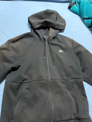 Lacoste zip  - De är en helt fin Lacoste zip till dig som vill sticka ut med en fin kofta som är använd några gånger och vill ha en skön kofta som värmer dig i denna kylan 
