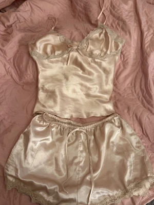 Pyjamas linne och shorts med spets - Säljer ett glansigt pyjamas set  i siden med tunna axelband och spetsdetaljer vid halsringningen.       Båda tillsammans 100kr, enskilt 50kr💗