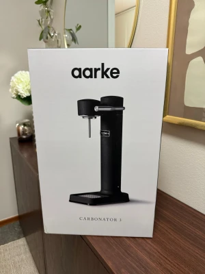 Aarke Carbonator 3 svart kolsyremaskin oöppnad!  - Snygg svart kolsyremaskin från Aarke, modell Carbonator 3. Maskinen har en stilren design i metall och levereras med en tillhörande PET-flaska. Perfekt för att göra bubbelvatten hemma på ett enkelt och elegant sätt.