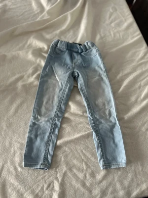 Ljusblå skinny jeans med resårmidja - Säljer ett par ljusblå skinny jeans med resår i midjan. Jeansen har klassisk femficksdesign och är tillverkade i mjukt denimtyg. Perfekta för en avslappnad och trendig look.