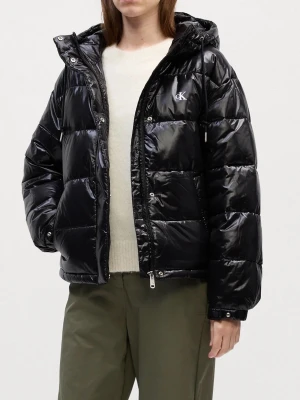 Svart pufferjacka från Calvin Klein - Snygg svart pufferjacka från Calvin Klein med glansig finish och diskret CK-logga på bröstet. Jackan har huva, dragkedja framtill och quiltad design som ger en modern vibe. Perfekt för kalla dagar när du vill hålla stilen.