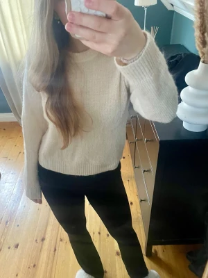 Vit stickad tröja med rund hals - Mysig vit/beige stickad tröja med rund hals och långa ärmar. Tröjan har en enkel, klassisk design. Perfekt för lager på lager och passar till det mesta.