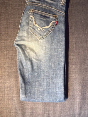 Blå Le Jean bootcut - Snygga blå jeans från Le Jean med ljusa slitningar och dekorativ brodyr på . Jag har använt dom kanske ungefär 3gånger så dom är precis som ny 💓pris kan diskuteras🤗köpta för 1200kr