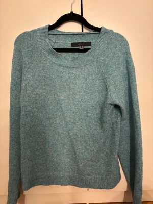 Blåmelerad stickad tröja Vero Moda - Mysig blåmelerad stickad tröja från Vero Moda. Tröjan har rund halsringning, långa ärmar och en avslappnad passform. Perfekt för lager på lager och enkel att matcha till jeans eller kjol. Materialet är mjukt och bekvämt.