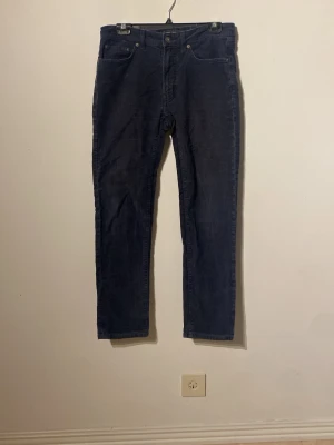 Mörkblå manchesterbyxor regular fit - Snygga mörkblå manchesterbyxor med klassisk rak passform och fem fickor. Byxorna har en tidlös look och är tillverkade i mjuk manchester som ger en skön känsla. Perfekta för dig som vill ha en stilren och avslappnad vibe. En av bältehällorna är av!