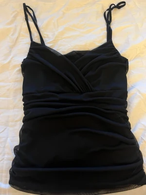 Svart linnetopp -  omlott linnetopp med rynkade detaljer längs sidorna. Storlek L men skulle söga att den är S/M