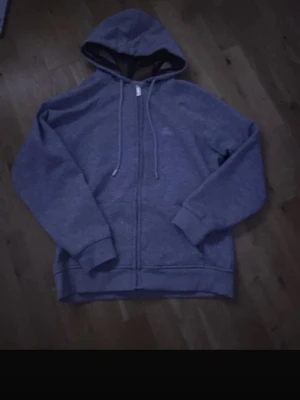 Grå zip-hoodie med dragsko - En enkel och stilren grå hoodie med dragkedja framtill och justerbar huva med dragsko. Tillverkad i mjukt sweatshirtmaterial och har ribbade muddar vid ärmar och nederkant. Perfekt för en avslappnad look. Storlek S sitter som xs helt ny jätte fin. Hör gärna av er om ni har frågor 