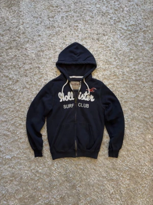 Hollister zip hoodie surf club blue - Snygg hoodie från hollister, använd men i gott skick. Mått: Längd: 65 Bröstvidd: 51 Ärm: 65