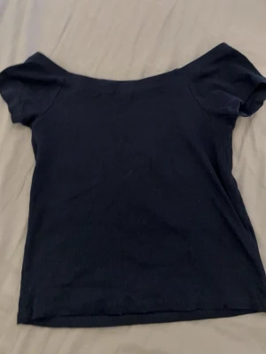 Mörkblå ribbad topp från Hailys - En enkel och stilren mörkblå ribbad topp från Hailys. Toppen har korta ärmar och en något bredare halsringning. Perfekt att matcha med jeans eller kjol för en clean look.