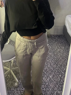 Beiga mjukisbyxor med snörning - Säljer ett par beiga mjukisbyxor med dragsko i midjan och fickor på sidorna. Byxorna har en avslappnad passform och är perfekta för chill dagar. Materialet känns mjukt och bekvämt mot huden.