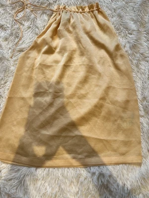 Beige omlottkjol med knytband - Gul topp! Jätte söt men har tyvärr inte kommit till användning Storleken kan varijera då men kan knyta den tajtare/ lösare i nacken men skulle säga xxs-s 