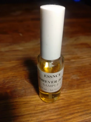 ESSNCE Forever June parfymprov - Liten parfymflaska från ESSNCE med doften Forever June. Flaskan är genomskinlig med vit kork och innehåller guldfärgad vätska. Provet är på 15 ml och har enkel, stilren design som passar i väskan.Denna doft har ännu inte släppts av ESSNCE, det är en somrig, blommig, söt doft.