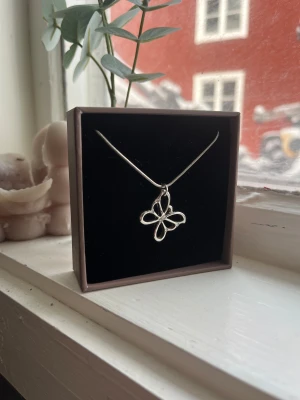 Silverhalsband med fjärilshänge - Snyggt halsband i silverfärg med ett stilrent fjärilshänge. Kedjan är tunn och smidig, och hänget har en öppen design som ger ett modernt intryck. Aldrig andvänd då den inte passar mig i stilen.