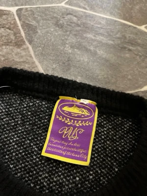 Svart stickad tröja från cortiez - Svart stickad tröja från Cortiez med diskret mönster i svart och grått. Tröjan har ribbstickad krage och är perfekt för dig som gillar en klassisk och stilren look. Materialet känns mjukt och passar bra till kyligare dagar.