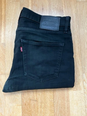 Svarta Levi's 512 jeans slim fit 32W 32L - Säljer ett par svarta Levi's 512 jeans med slim passform. Klassisk femficksmodell med Levi's logga på bakfickan och svart patch bak i midjan. Snygg, tidlös design i stretchigt jeanstyg som sitter riktigt bra.