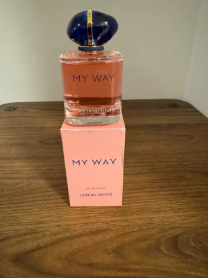Giorgio Armani My Way EdP 90ml - Upptäck My Way Eau de Parfum från Giorgio Armani. Flaskan är elegant med rosa doftvätska och en djupblå, rundad kork med gulddetaljer. Förpackningen är ljusrosa med blå text. En modern och fräsch parfym som utstrålar lyx och stil.