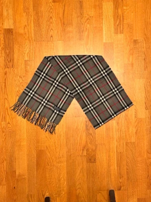 Grå Burberry halsduk - Säljer en grå halsduk från Burberry. Halsduken är i fint skick och är gjord i 100% grå. Var inte rädd för några frågor. Pris diskuteras inte!