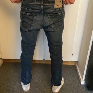 Jacob Cohën blå jeans, storlek 32 - Snygga blå jeans från Jacob Cohën i storlek 32. Klassisk femficksmodell med mörk tvätt och kontrastsömmar. Handgjorda med exklusiva material och italienskt hantverk. Jeansens passform är rak och de har en normal midja. Perfekt för dig som gillar stilrena detaljer.