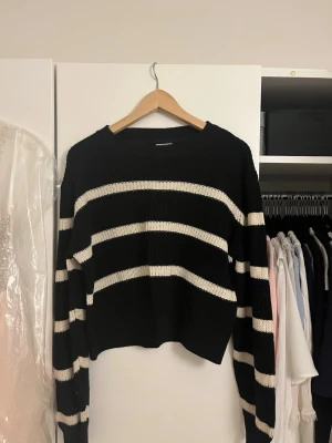 Svartvit randig stickad tröja - Snygg stickad tröja med breda svarta och vita ränder. Tröjan har en avslappnad passform, rund halsringning och långa ärmar. Perfekt för en chill och trendig look. Materialet känns mjukt och bekvämt mot huden. Size S