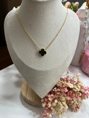 18k guldpläterad klöver halsband  - Ett mycket fint halsband i rostfritt stål, pläterat med 18K guld, med en stilren klöver i svart 15 mm. Supertrendigt och perfekt för både vardag och fest.  Scrolla gärna vidare på sidan för att hitta matchande armband som kompletterar halsbandet perfekt.