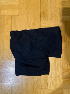 Svart offshoulder topp - Snygg svart offshoulder topp med åtsittande passform och diskret struktur i tyget. Perfekt att styla med jeans eller kjol för en trendig look. Toppen är ärmlös och har en croppad känsla som framhäver axlarna.