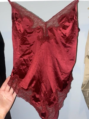 Vinröd body - En vi röd body som har spets både uppe och nere med ett tunt material så är bra att användas på sommaren eller festtillfällen