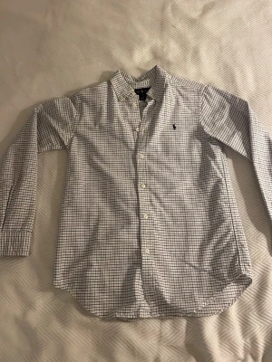 Ralph lauren skjorta - Stilig rutig skjorta från Ralph Lauren. Skjortan har lång ärm, knappar framtill och den ikoniska broderade loggan på bröstet. 