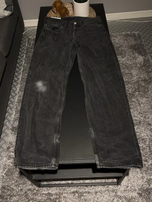 Svarta raka jeans - Säljer ett par svarta jeans med rak passform och klassisk femficksdesign. Jeansen har en diskret tvättad look och är tillverkade i denim. Perfekta för dig som gillar en enkel och stilren stil.