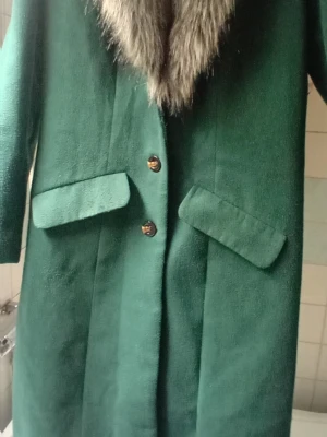 Jättefin kappa - Jättefin o varm kappa som jag tycker är smaragdgrön i färgen och lite lätt figursydd.. Avtagbar päls om man vill. Kappan är endast använd vid ett fåtal tillfällen. 