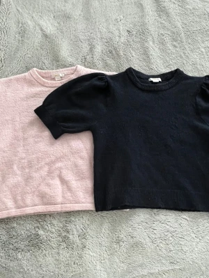 Marinblå & ljus rosa stickade tröjor med puffärm - Marinblå och rosa stickad tröja med korta puffärmar och rund halsringning. Tröjan har ribbstickade muddar vid ärmslut och nederkant. Perfekt för lager-på-lager och enkel att matcha med olika outfits.pris går att diskutera!