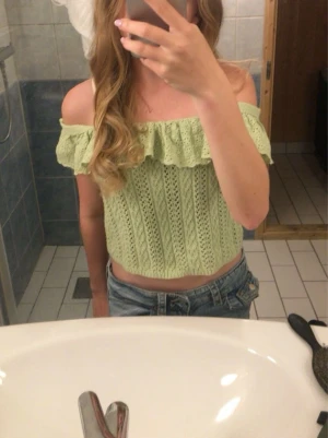 Grön offshoulder stickad topp - Söt ljusgrön offshoulder topp med volangkant och hålstickat mönster. Toppen är croppad och har en romantisk vibe med spetsdetaljer längs axlarna. Perfekt för varma dagar och somriga outfits.