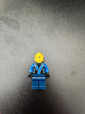 Blå LEGO-figur med tryckt dräkt - Säljer en klassisk LEGO-minifigur med blå ben och blåsvart överkropp med tryckt dräkt och detaljer i vitt och svart. Huvudet är gult och händerna svarta. Perfekt till samlingen eller för att bygga egna äventyr.
