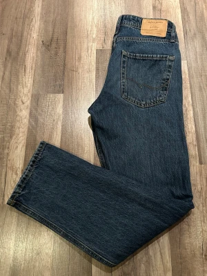 Mörkblå raka jeans från Jack & Jones  - Säljer ett par mörkblå jeans från Jack & Jones med klassisk femficksmodell och raka ben. Jack & Jones relaxed/chris med en normal midja och är tillverkade i slitstark denim. Perfekta för en avslappnad och trendig look. Storlek W28 L32