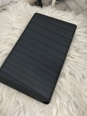 Samsung surfplatta svart - Snygg svart surfplatta från Samsung med stilren design och slimmad form. Baksidan är matt och har en liten kamera i hörnet. Perfekt för att streama, surfa eller plugga på. Materialet känns robust och modern.