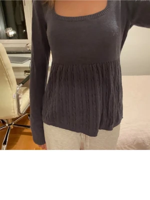 Mörkblå Hollister babydoll  - Mysig mörkgrå stickad tröj med rund halsringning och lång ärm. Nedre delen har ett snyggt kabelstickat mönster som ger extra struktur och volym. Perfekt för lager-på-lager och enkel att matcha med olika outfits.