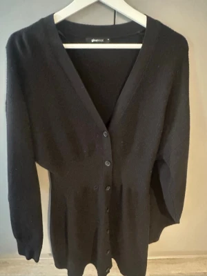 Svart stickad klänning  - Svart stickad klänning  från Gina Tricot med v-ringning, intagen midja och knappar framtill.
