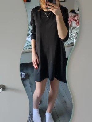 Svart enkel kortklänning med trekvartärmar och fickor - Svart kortklänning med rund hals och trekvartsärm. Knappt använd! Klänningen har:  • två praktiska fickor framtill  • mjukt, lite stretchigt material som känns bekvämt mot huden.  • Passformen är loose och modellen är stilren och minimalistisk. 