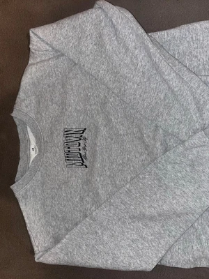 Grå sweatshirt från H&M med tryck - Säljer en stilren grå sweatshirt från H&M med svart tryck på bröstet där det står 'Midtown'. Tröjan har rund halsringning och är gjord i mjukt bomullsmaterial. Perfekt för en avslappnad och trendig look.