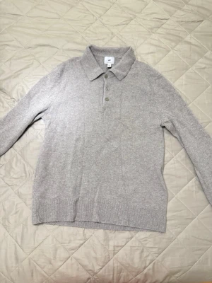 Beige stickad tröja från H&M - Säljer en beige stickad tröja från H&M med klassisk krage och tre knappar framtill. Tröjan har lång ärm och ribbade muddar vid ärmslut och nederkant. Perfekt för dig som gillar en enkel och stilren look.