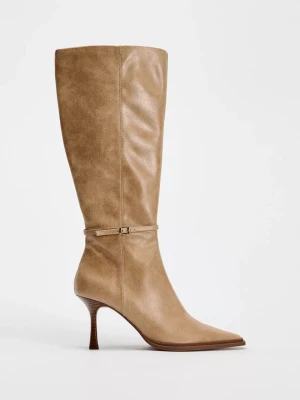Beiga höga stövlar med smal klack från Zara  - Snygga knähöga stövlar i beige konstläder med spetsig tå och smal klack. Dekorativt spänne runt ankeln ger en trendig touch.