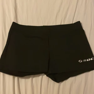 Svarta träningsshorts från SOC - Svarta, tighta träningsshorts från SOC med diskret logga på ena benet. Perfekta för gymmet eller löprundan, tillverkade i stretchigt syntetmaterial som ger bra rörelsefrihet.nyskick!!