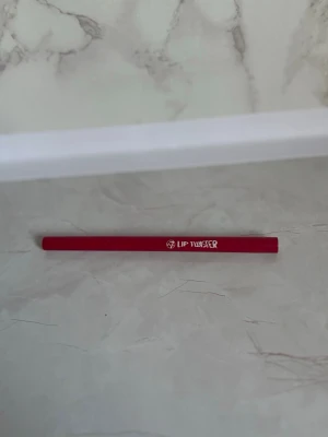 W7 Lip Twister röd läppenna - Säljer en W7 Lip Twister läppenna i en snygg röd nyans. Pennan har en smal och vridbar design som gör det enkelt att applicera färgen exakt på läpparna. Perfekt för att skapa definierade läppkonturer eller fylla i hela läpparna med intensiv färg.