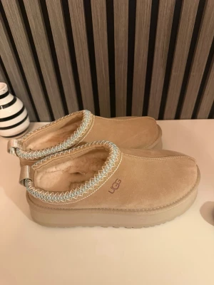 Beige UGG tofflor med fårfoder - Säljer ett par beiga UGGS i storlek 40, skorna är aldrig andvända då jag fick dom i fel storlek🤍bara att höra av sig för fler frågor!