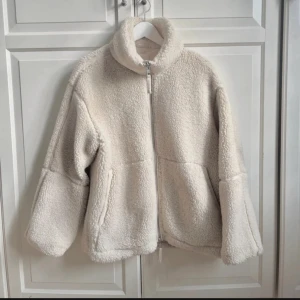 Teddyjacka från H&M - Supermysig teddyjacka från H&M i beige färg med hög krage och dragkedja framtill. Jackan har två stora fickor och en loose passform som ger en chill vibe. Perfekt för att hålla sig varm och se snygg ut under höst och vinter. Sista bilden är lånad 🥂💗