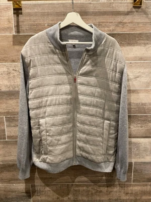 Reiss Mocka jacka  - Snygg grå jacka med quiltad front och mjuka, stickade ärmar. Jackan har dragkedja framtill, ståkrage och två fickor. Perfekt för lager-på-lager och en clean streetstyle-look.