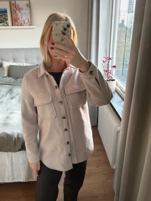 Vårjacka - Snygg beige overshirt med stora bröstfickor. Knäpps med knappar framtill. 