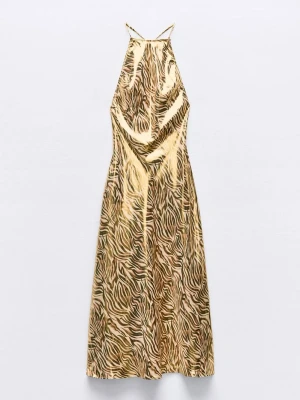 Zebramönstrad långklänning i satin - Cool långklänning från Zara i beige och svart zebramönster. Klänningen har tunna axelband och halterneck, vilket ger en trendig och elegant look. Tillverkad i glansigt satinmaterial som känns lyxigt och faller snyggt.