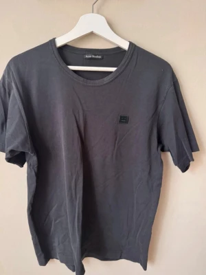 Svart t-shirt från Acne Studios - Snygg svart t-shirt från Acne Studios med klassisk rund hals och diskret logopatch på bröstet. Tillverkad i mjuk bomull och har en normal passform. Perfekt basplagg för alla tillfällen.