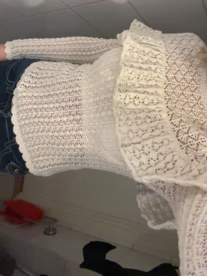 Vit virkad off shoulder stickad tröja - Säljer en vit stickad tröja och bred volang runt axlarna. Tröjan är använd fåtal gånger och är perfekt för fest, middagar m.m